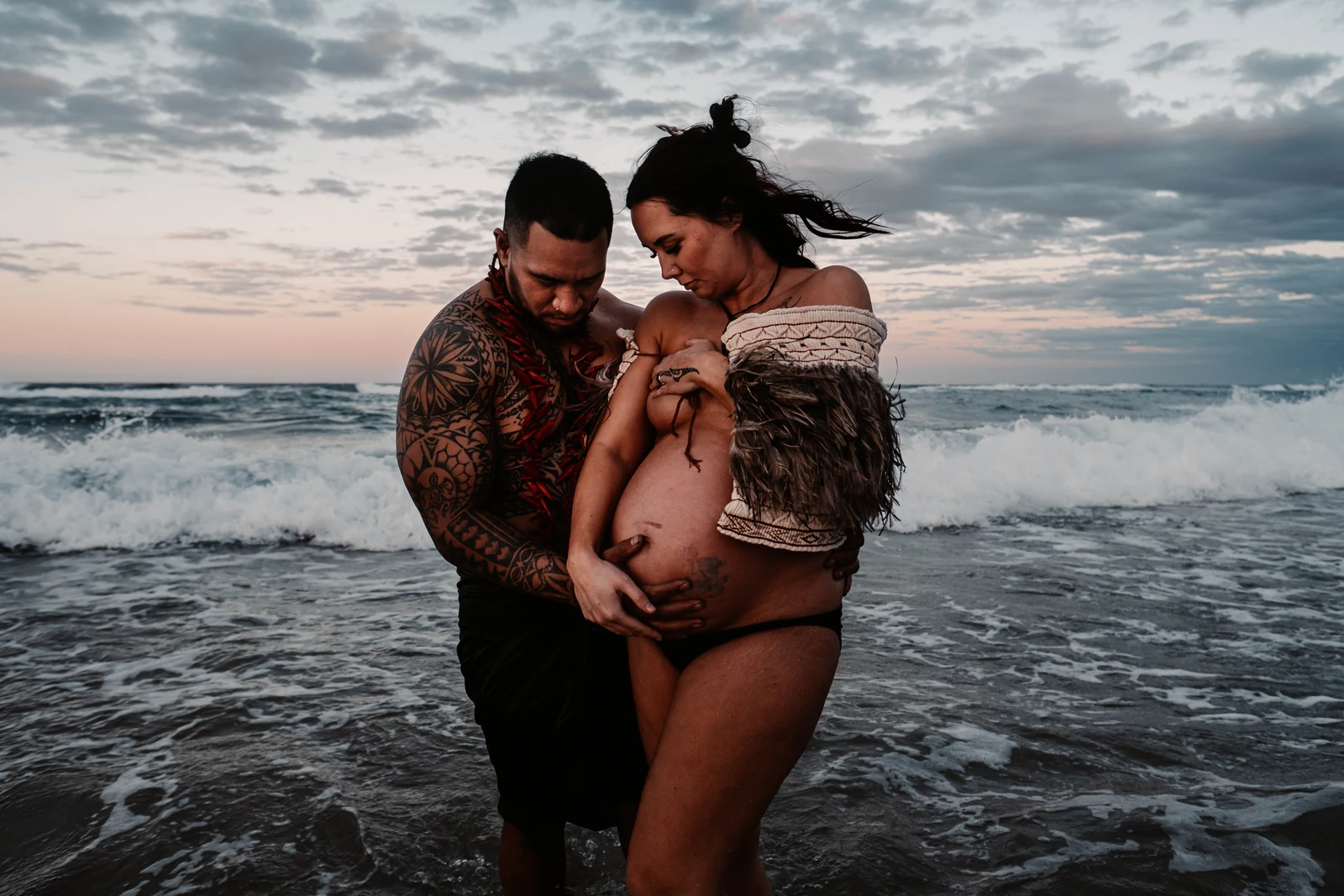 Shanell and Shonrae embracing by the ocean during their maternity session
