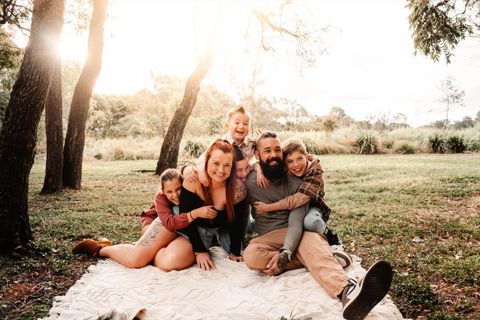 Family laughing together beneath trees in golden light